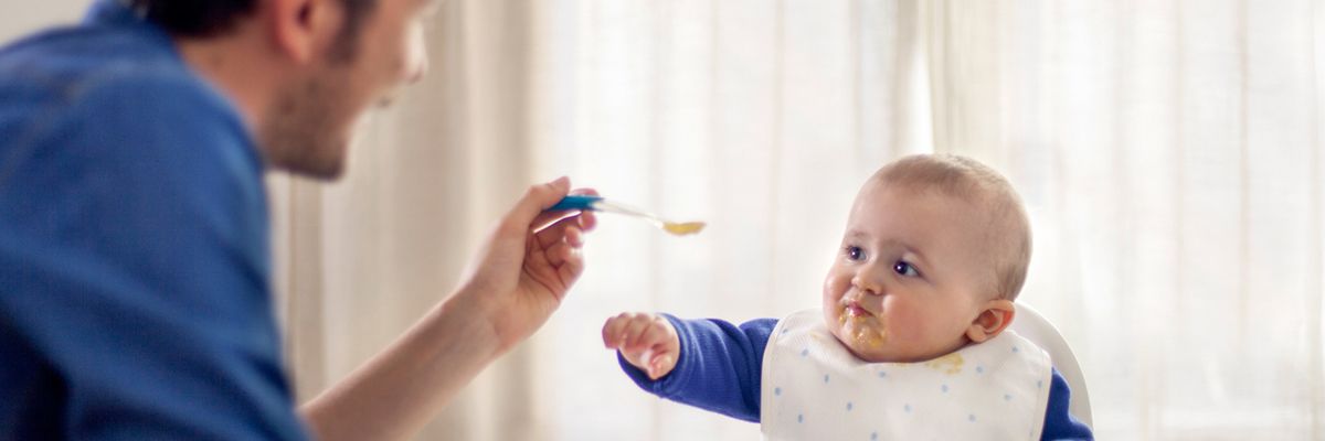 Vater füttert Baby mit Brei
