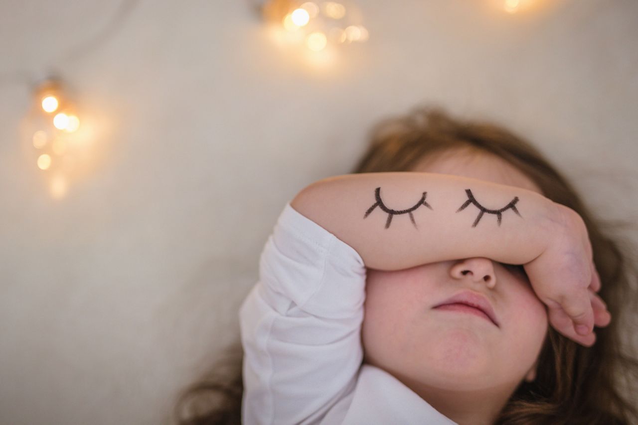 Kleinkind verdeckt sich mit dem Arm die Augen