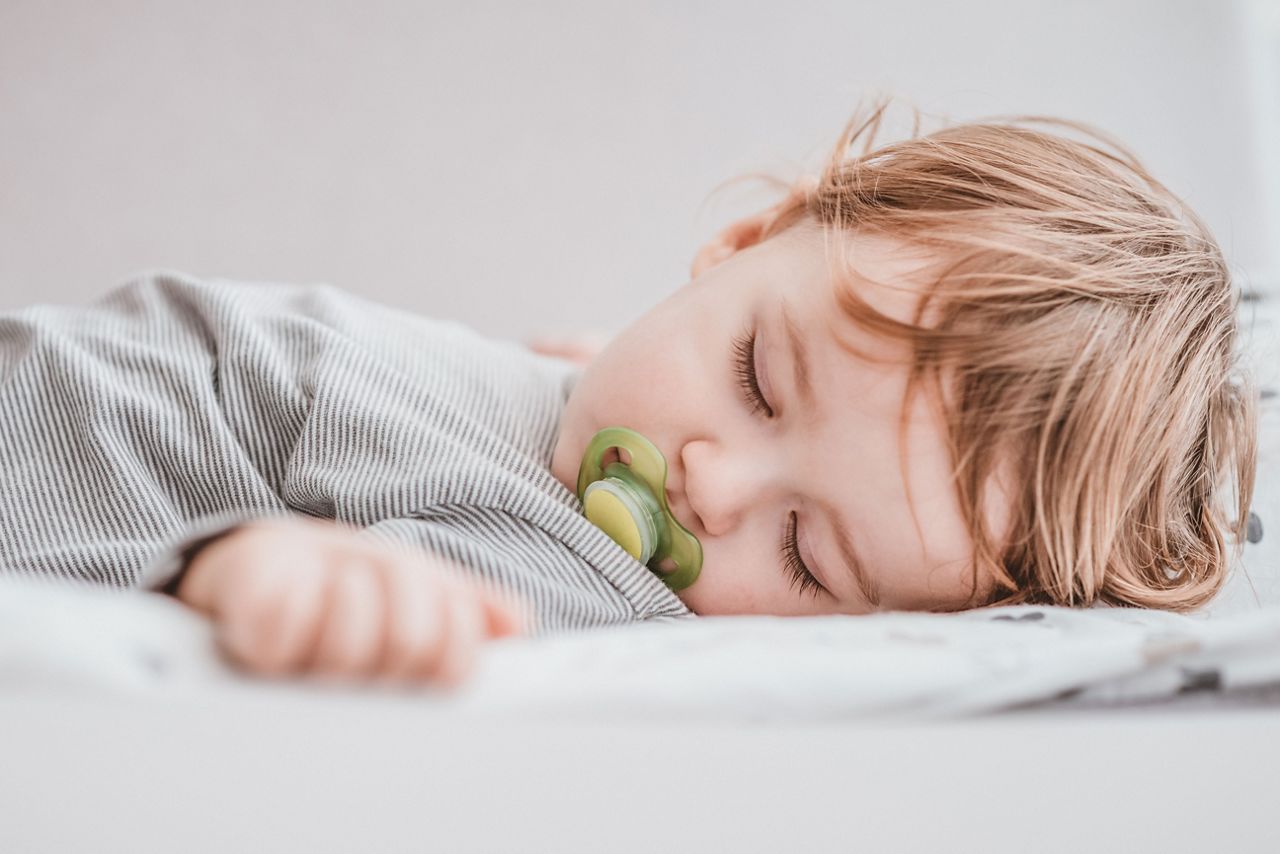 Kleinkind verdeckt sich mit dem Arm die Augen
