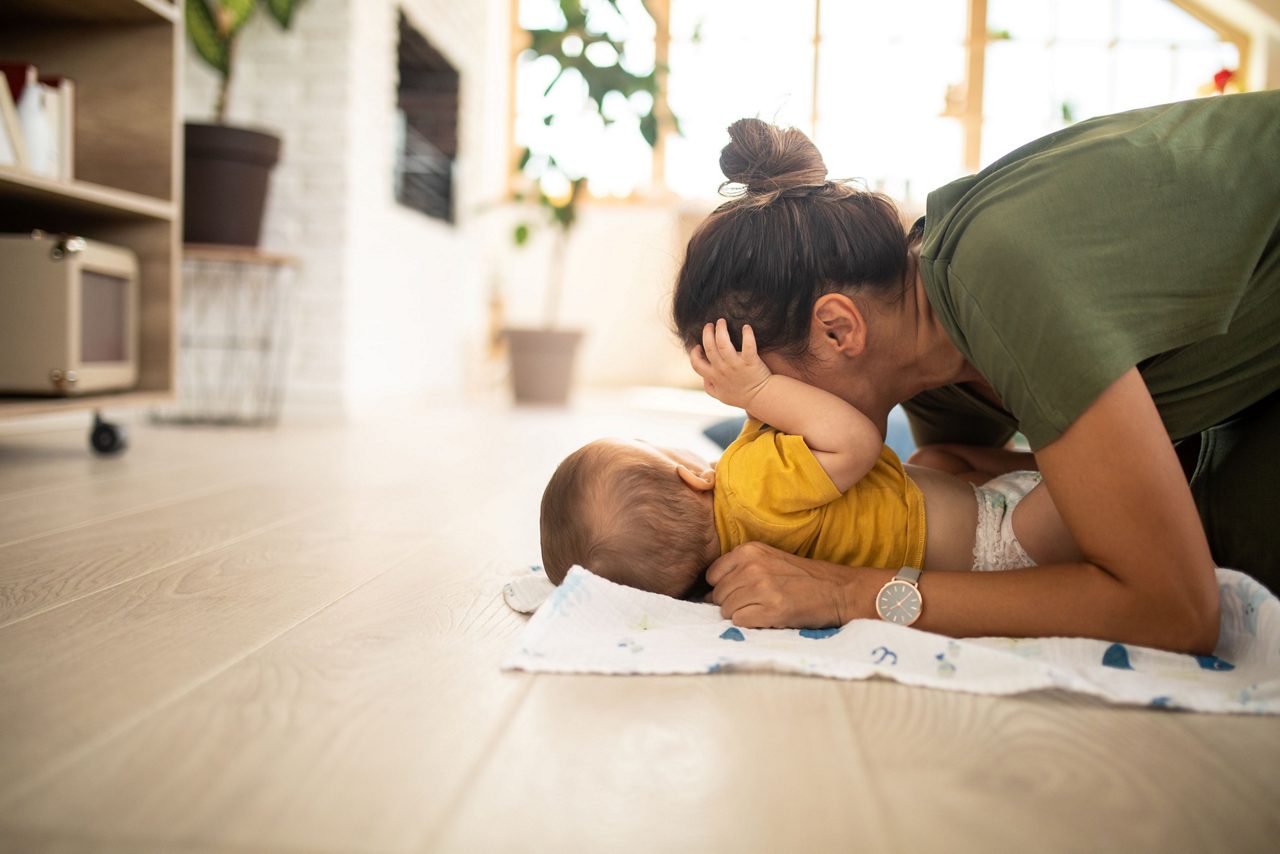 Baby liegt auf dem Rücken und kuschelt mit Frau