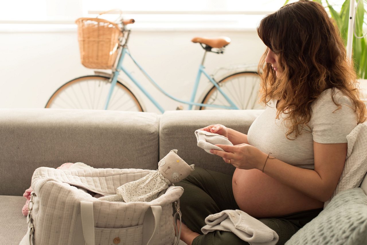 Frau hält Babybauch und schaut Fotos an