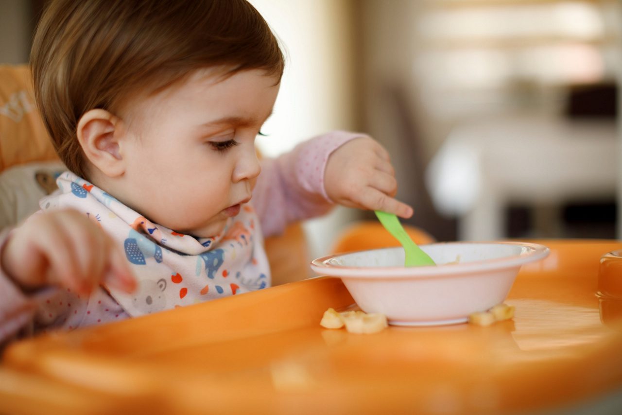 Baby isst Brei mit Löffel