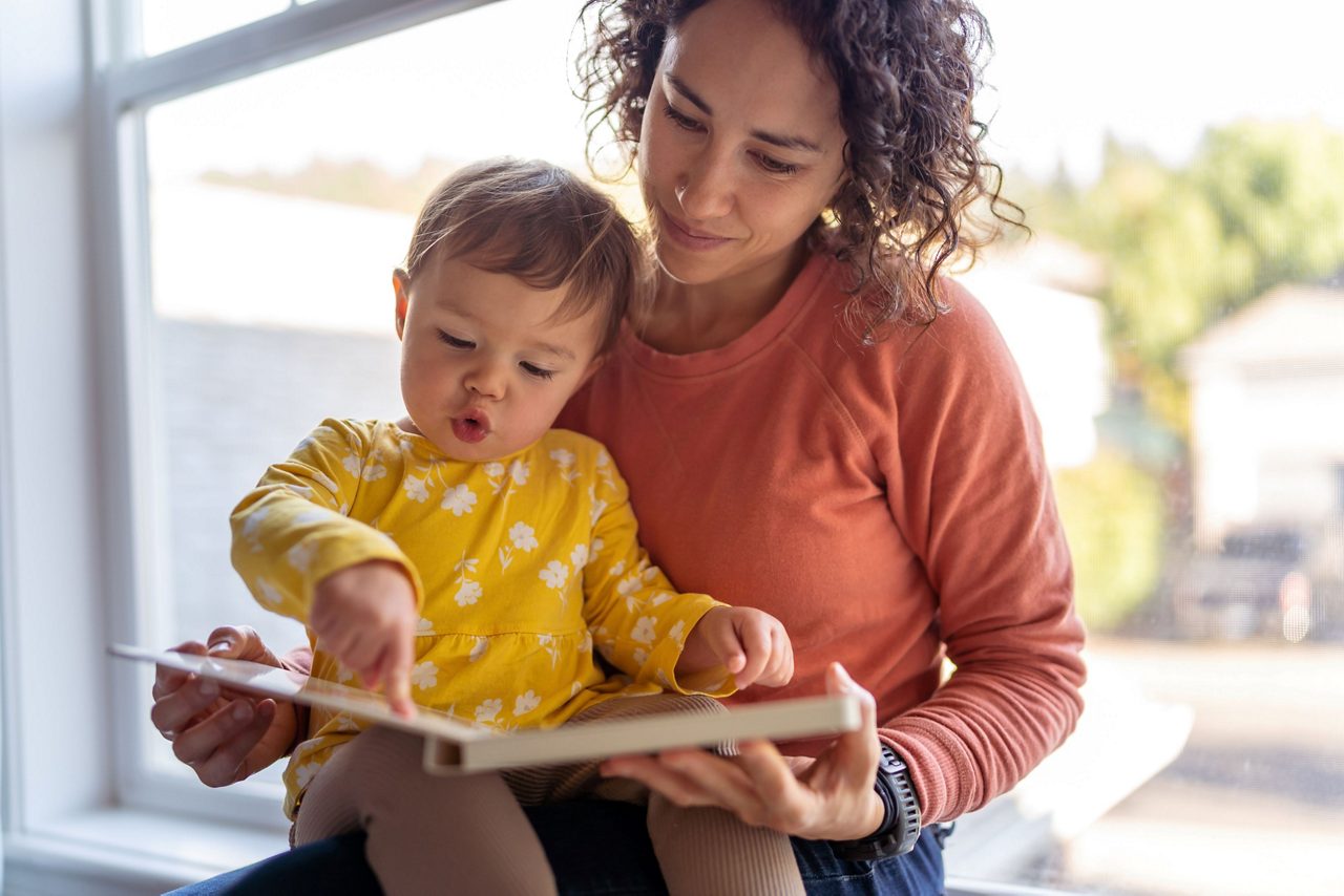 Mutter und Kleinkind blicken auf Kinderbuch