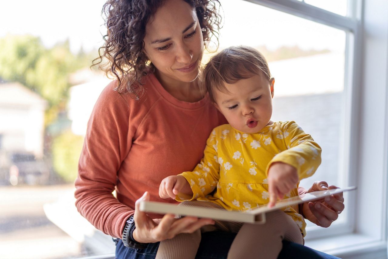 Mutter und Kleinkind blicken auf Kinderbuch
