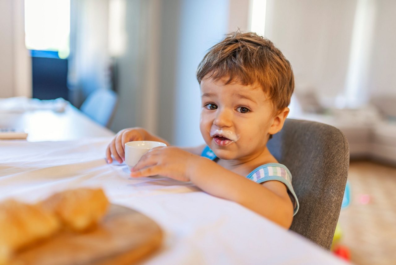 Kleinkind mit einem Glas Milch in der Hand