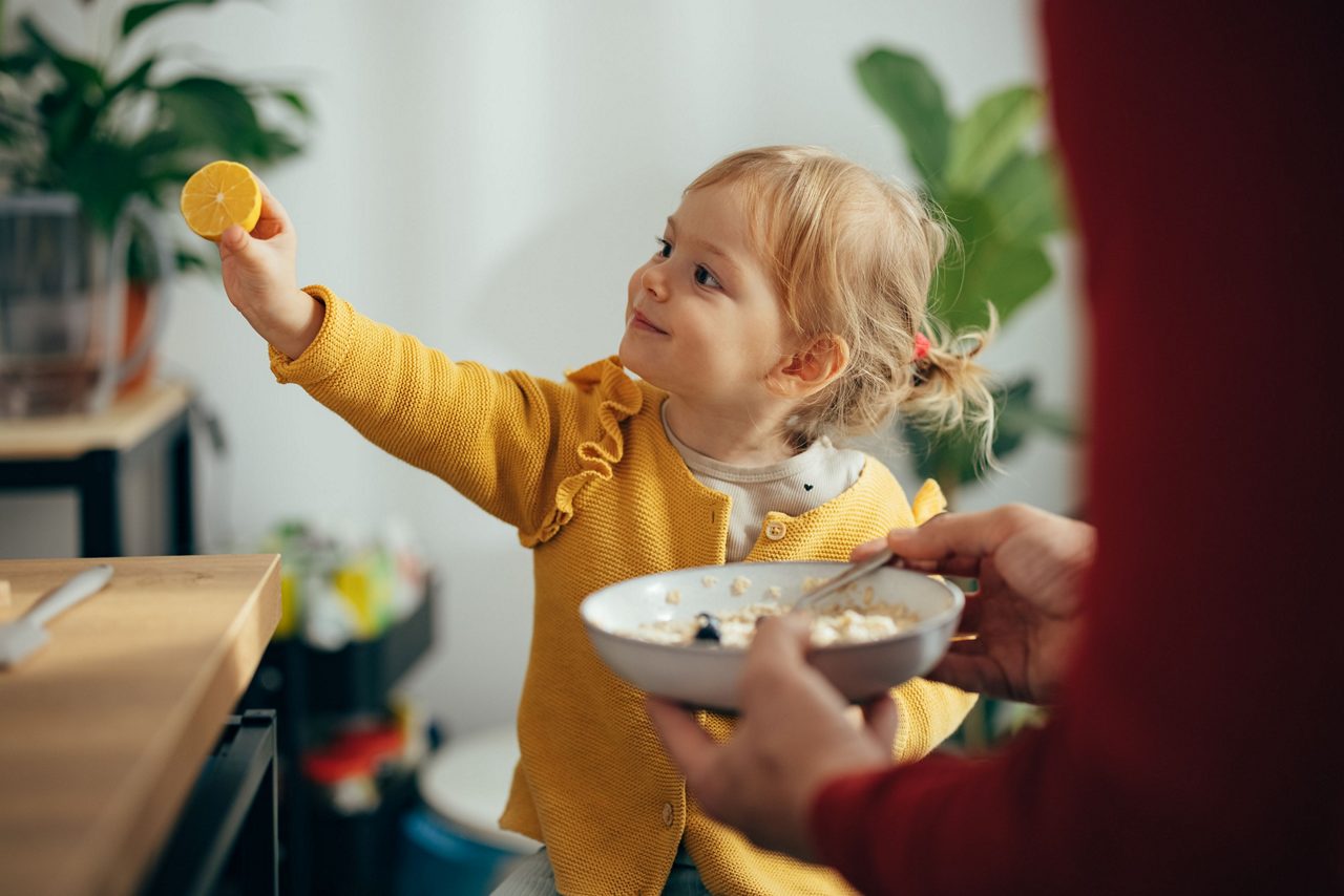 Kleines Mädchen hält Orange in der Hand