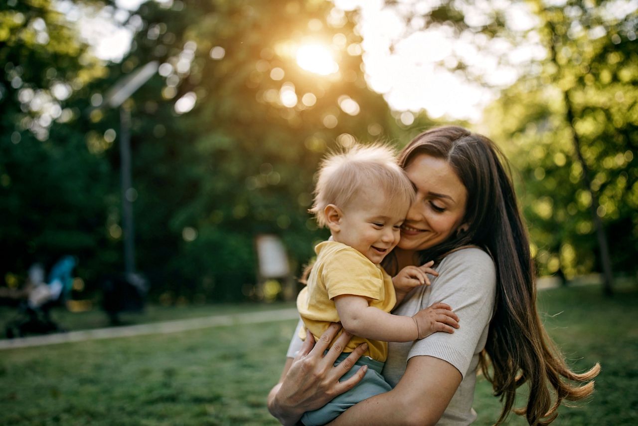 Mutter mit Blume im Haar hält Baby