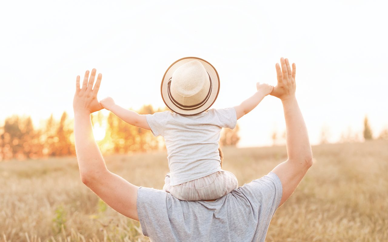 Vater trägt Kleinkind auf den Schultern in der Natur