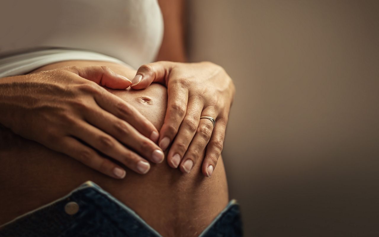 Schwangere hält Bauch in Herzform Nahaufnahme
