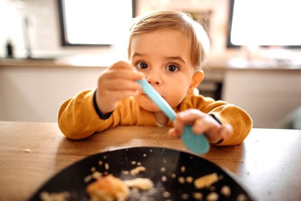 Mama füttert Baby mit Löffel Brei