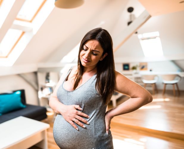 Schwangere Frau mit Schmerzen hält Babybauch