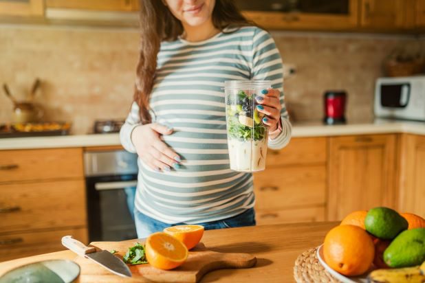 Schwangere bereitet Smoothie zu 