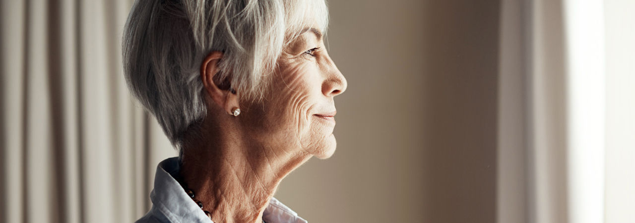 Cropped shot of a senior woman looking out the window at home