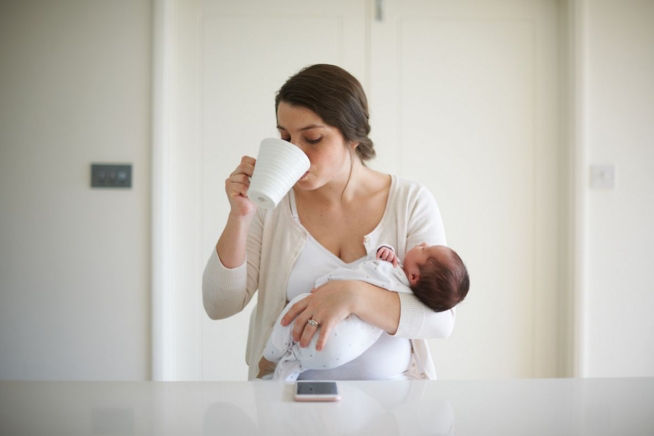 mother having coffee while holding baby