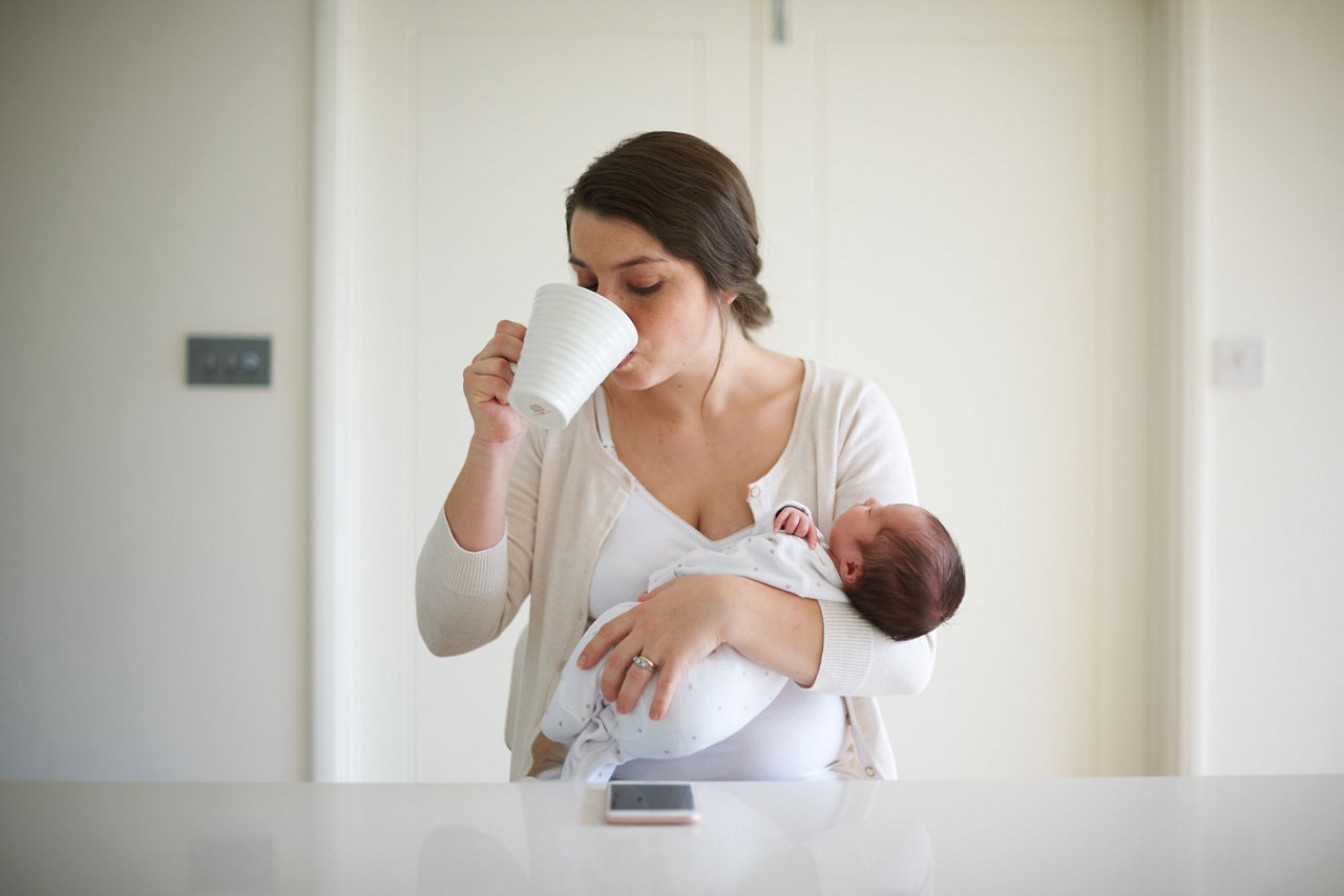 mother-having-coffee-while-holding-baby