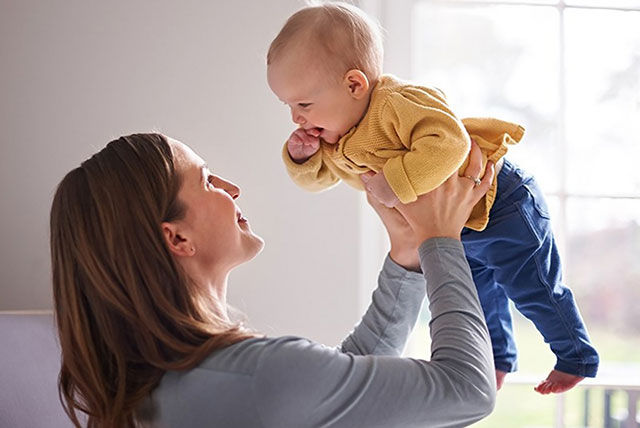 mother holding up baby