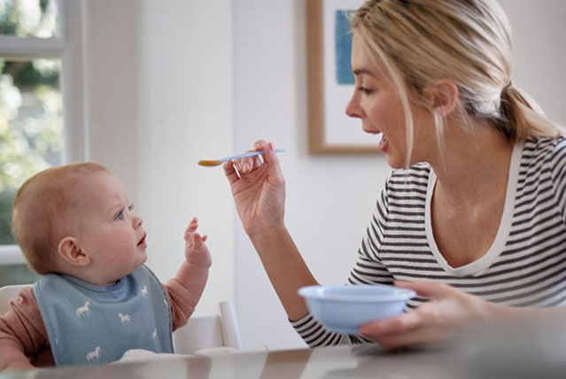 mother spoonfeeding baby