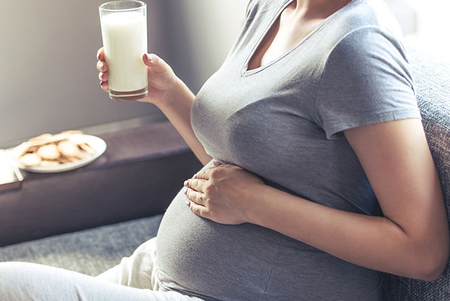 mujer embarazada tomando leche con galletas