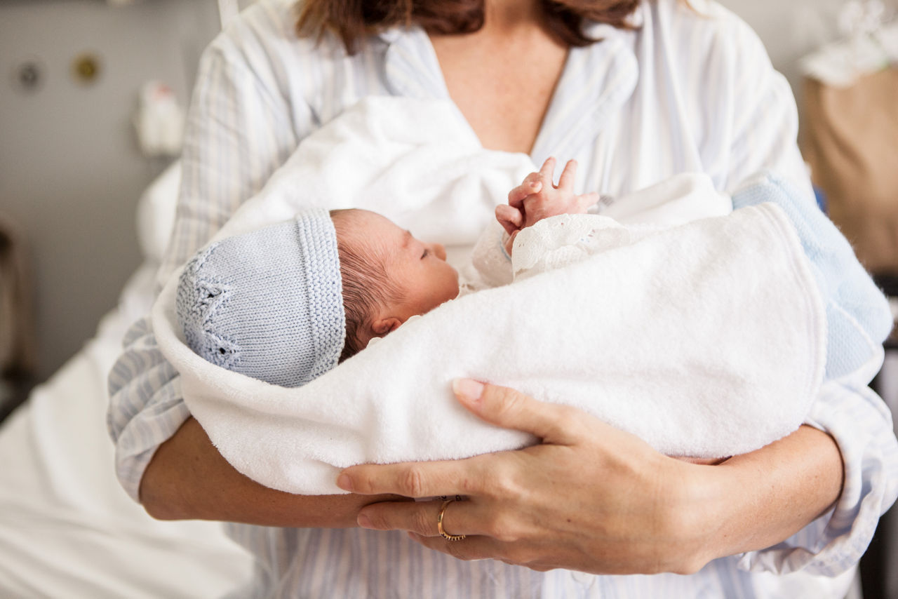 Mother holding her newborn baby in hospital bed