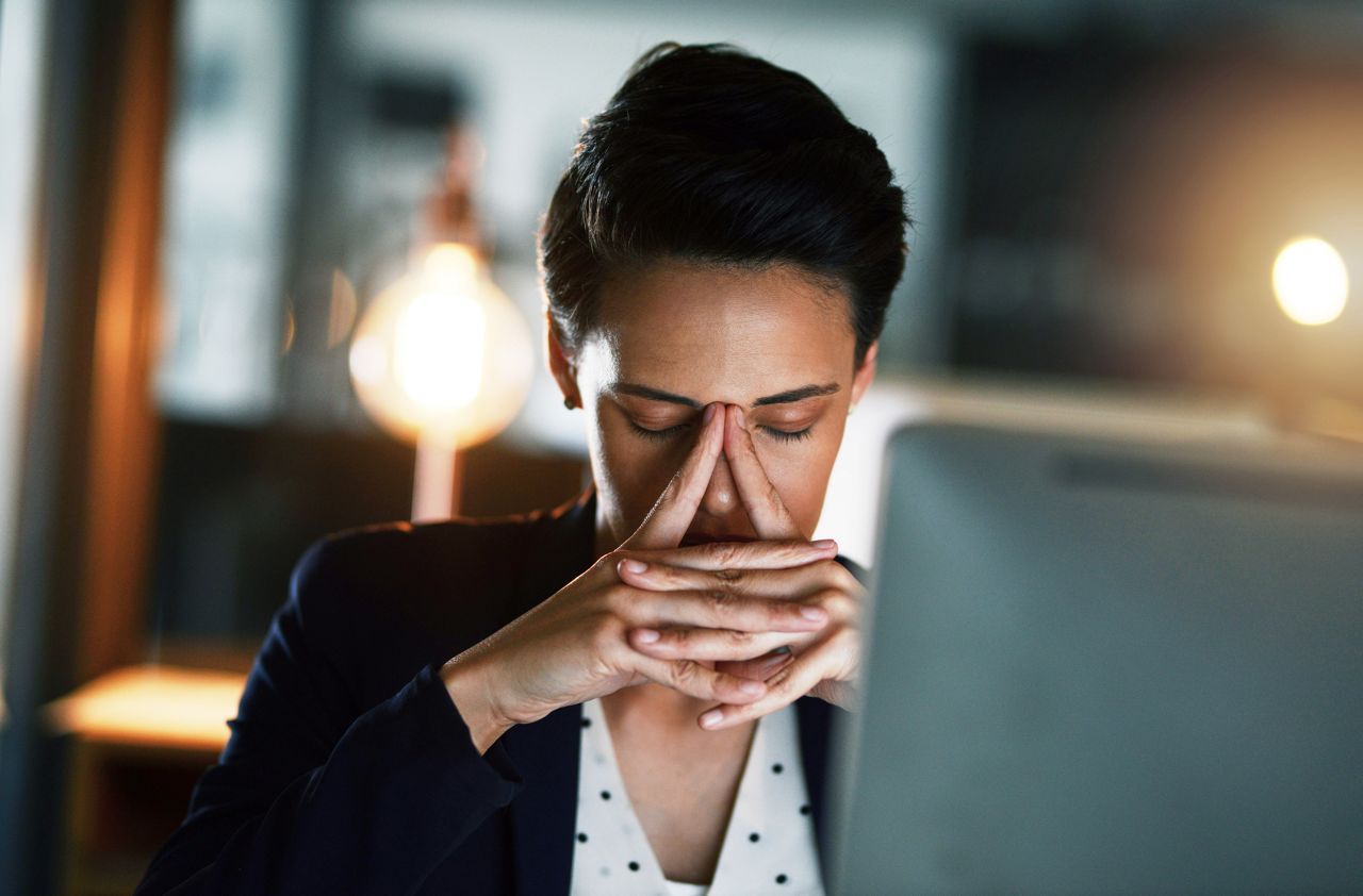 Shot of a young businesswoman looking stressed out while working late in an office