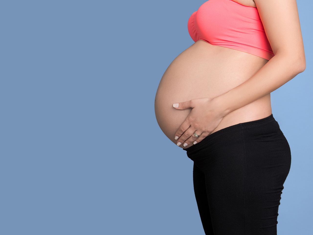 Pregnant woman standing on blue background, Studio shot