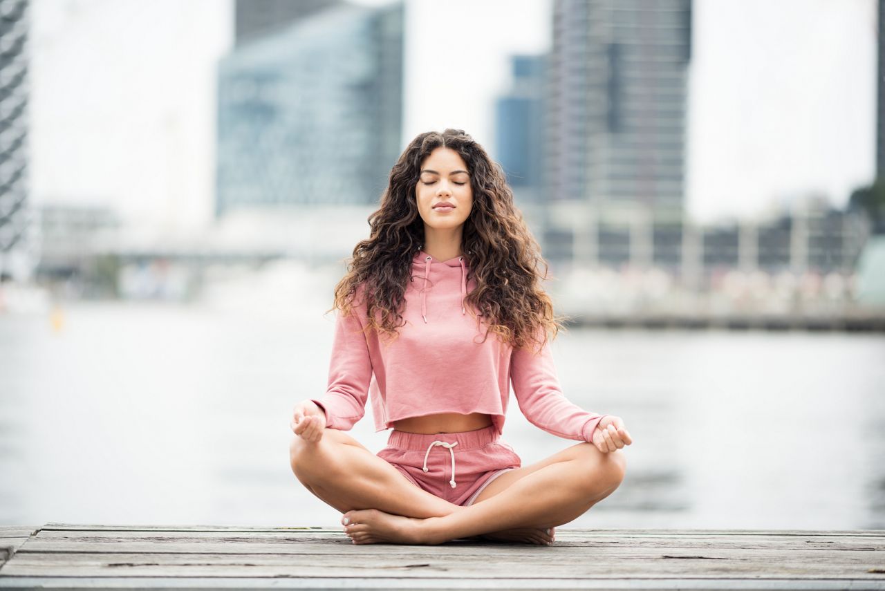 Woman meditating in a relaxing pose. Downtown. Nikon D810. Converted from RAW.