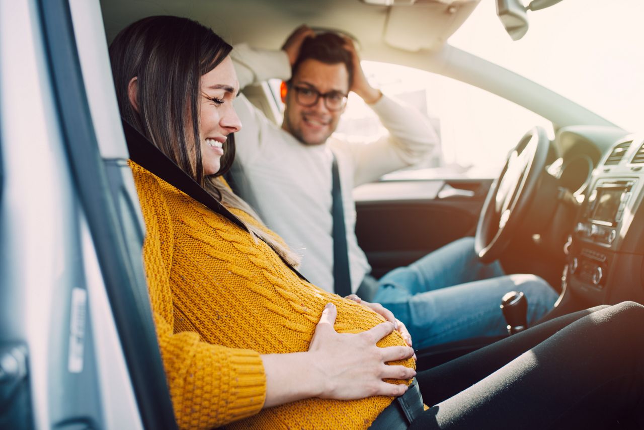 Pregnant woman starting to feel pain and contractions while her worried husband driving a car. She is ready to give birth in a car."n