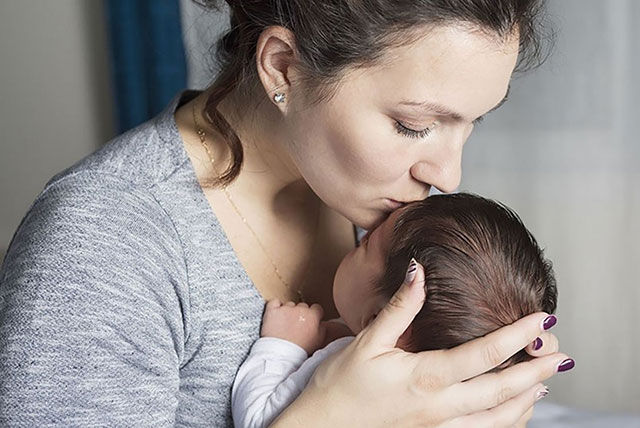 mum kissing newborn on forehead