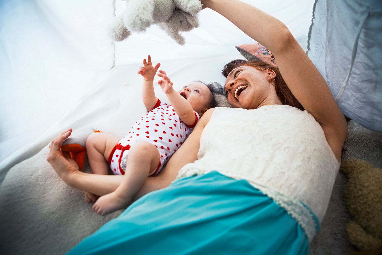 Mum laying with baby on couch playing