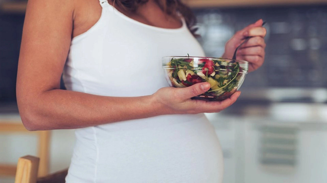 Pregnant woman eating salad