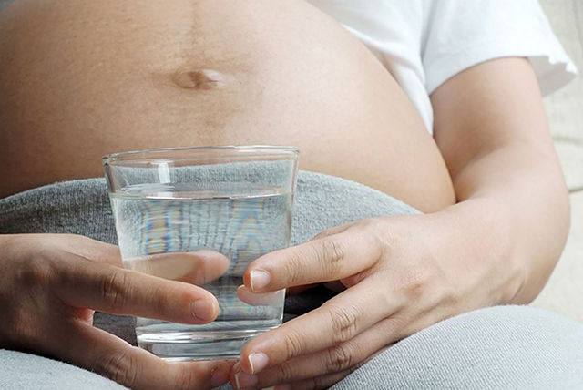 mujer embarazada de 36 semanas sosteniendo un vaso con agua