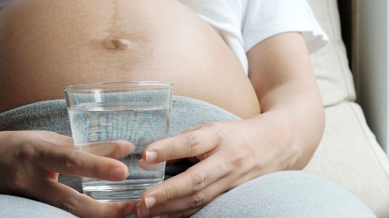 Mum to be holding glass of water 