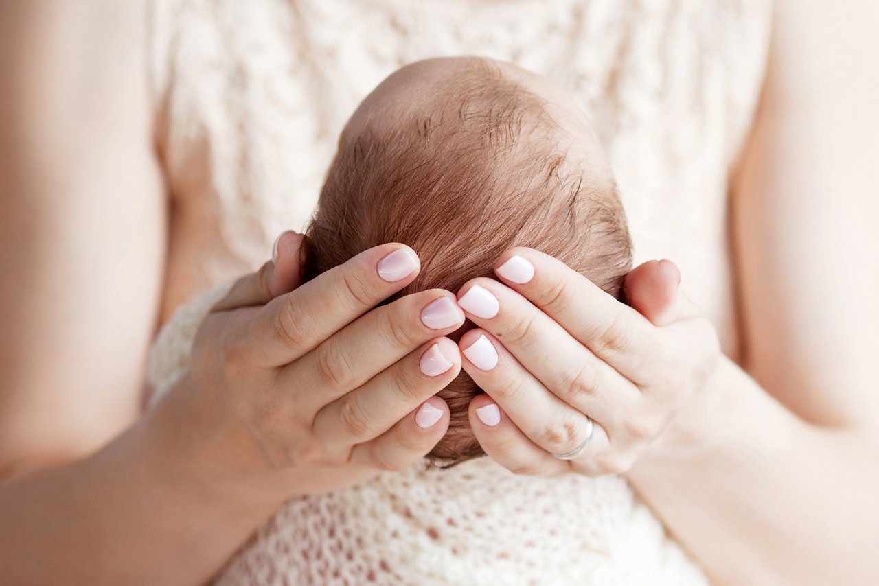 Mother holding head of her newborn baby in hands. The baby on hands at mum. Loving mother hand holding cute newborn baby child getty images