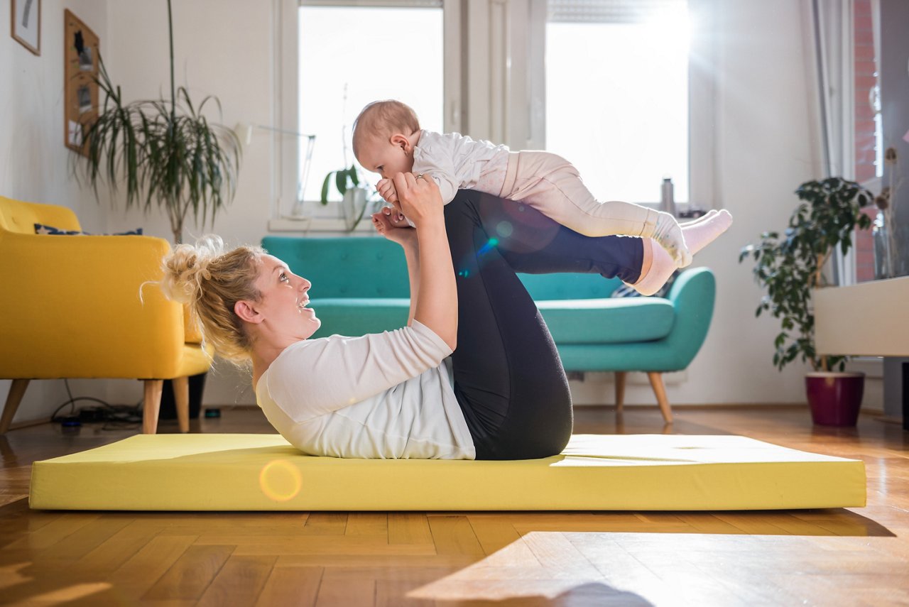 Mother Exercise With Her Baby on yellow mat At Home getty images 657772922