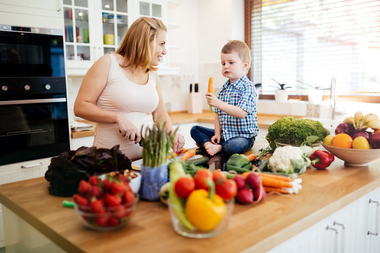 Pregnant woman preparing meal with son from fresh vegetables getty images 541147472