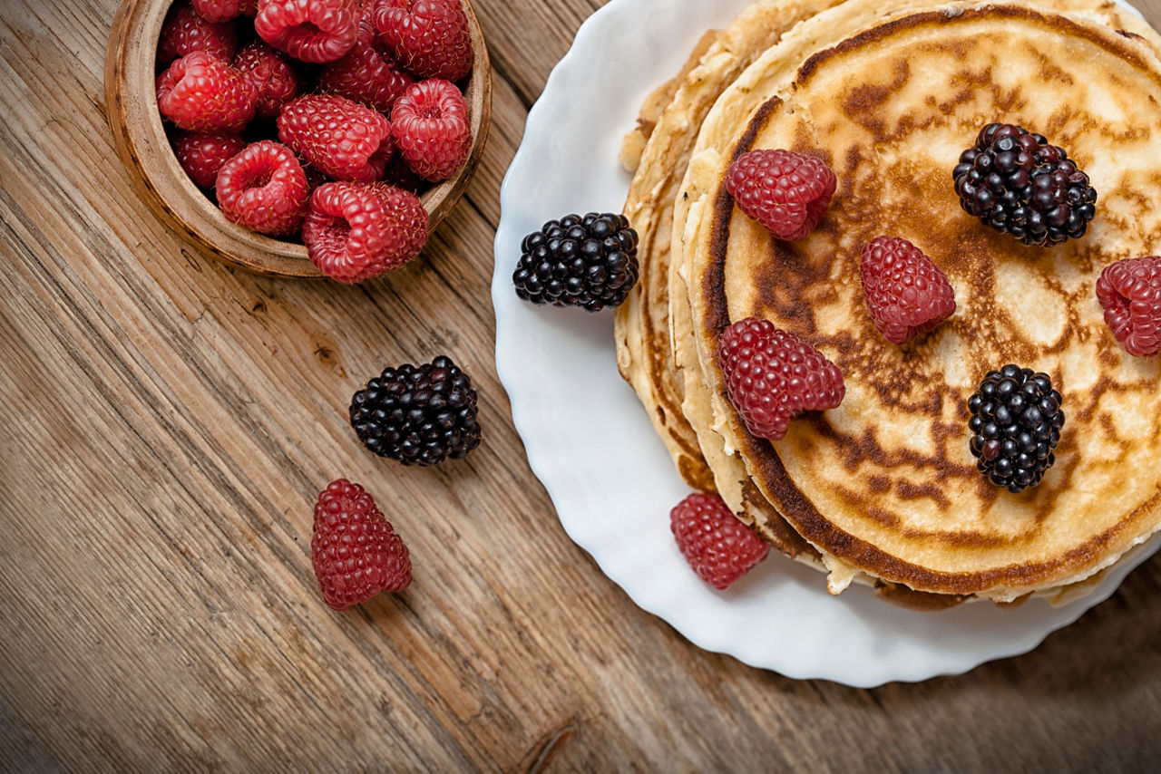 Delicious pancakes with berries on the wooden table