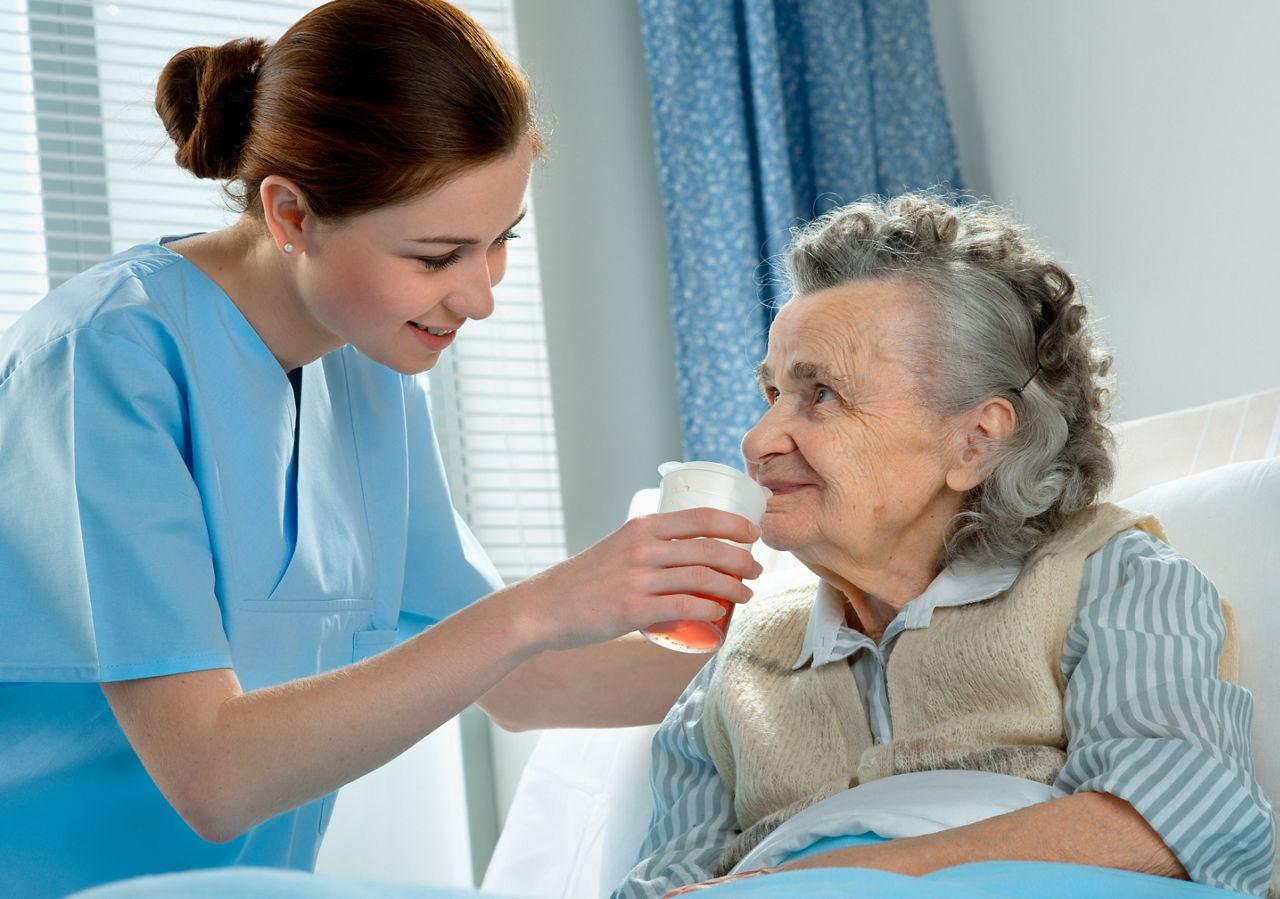 Nurse helping a senior woman drink some water