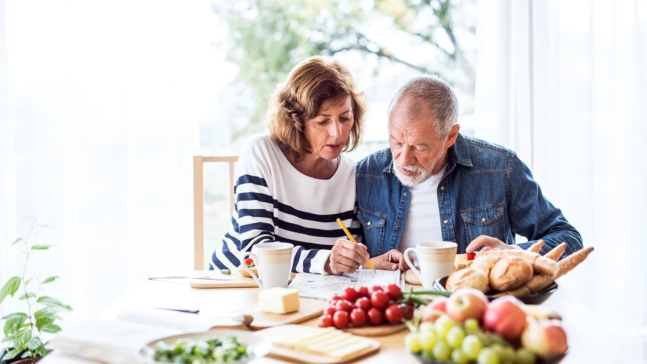 Senior couple sitting at a table full with vegetables and fruits