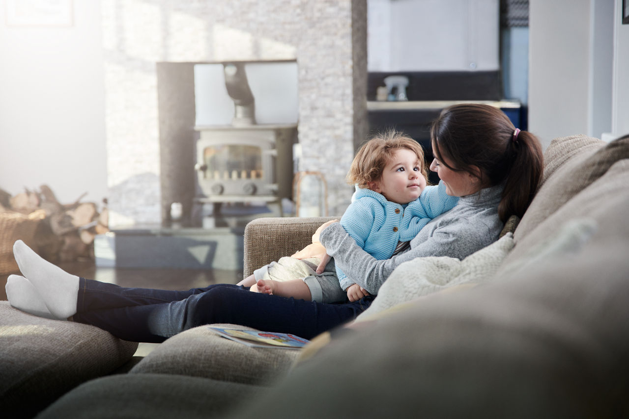 Mother sittin on a couch holding her daughter in her arms