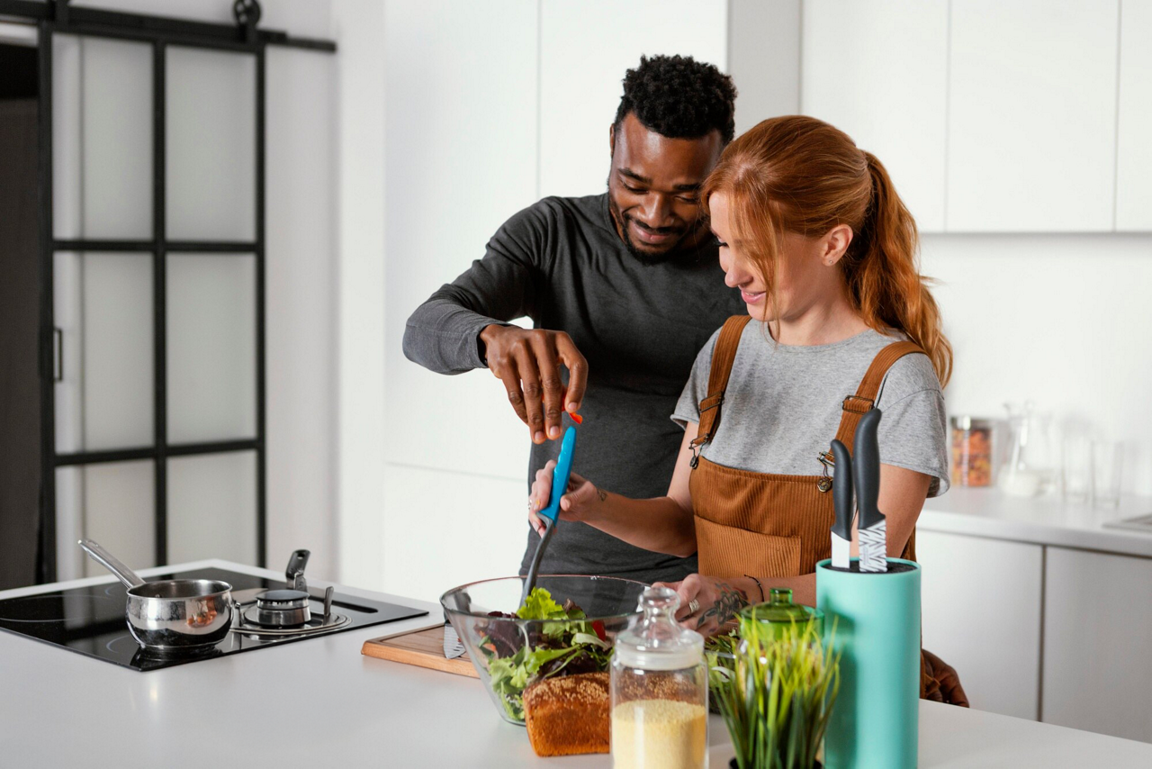 Romantisch koppel kookt samen in de keuken, glimlacht en geniet van elkaars gezelschap.