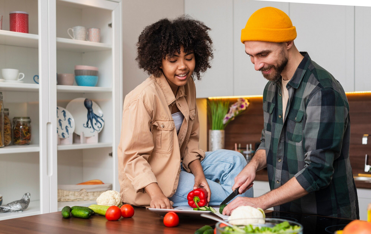 Happy couple chopping fresh vegetables together in the kitchen.
