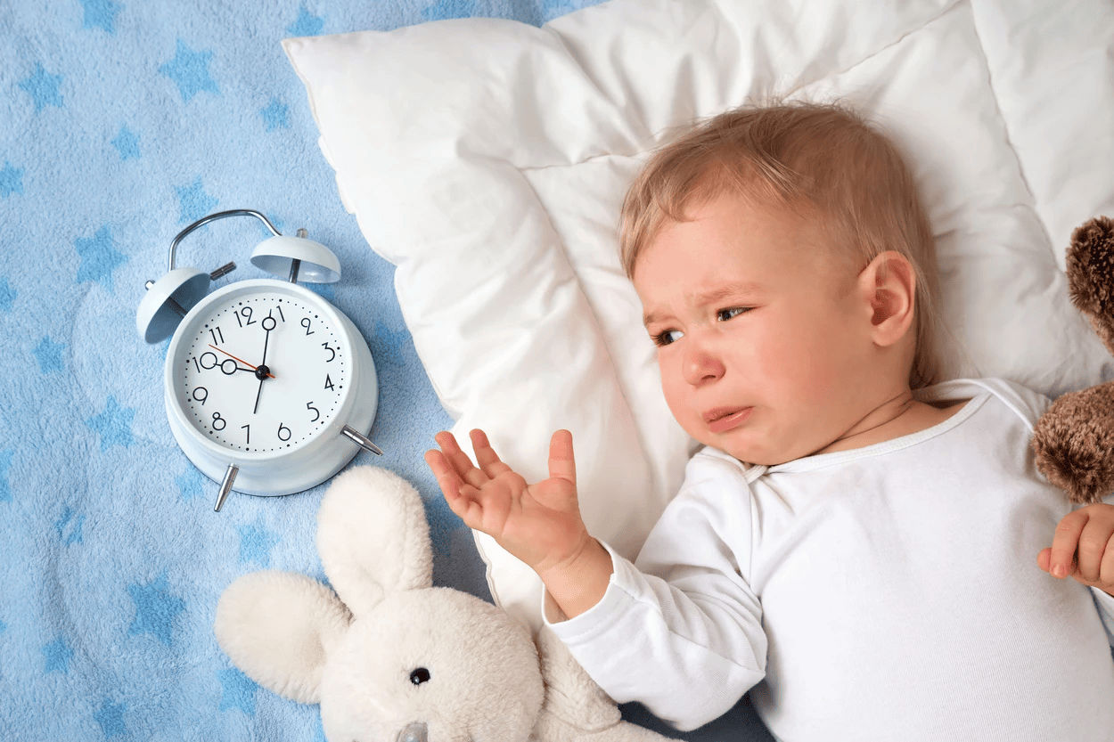 Baby with alarm clock in bed