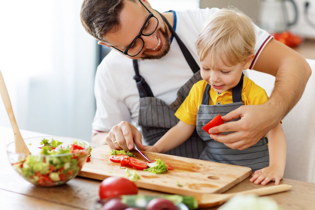 happy family father with son  preparing vegetable salad at home