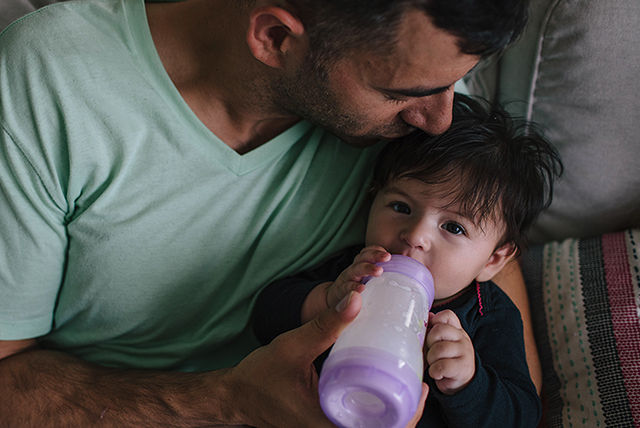 papá alimentando a su bebé con biberón