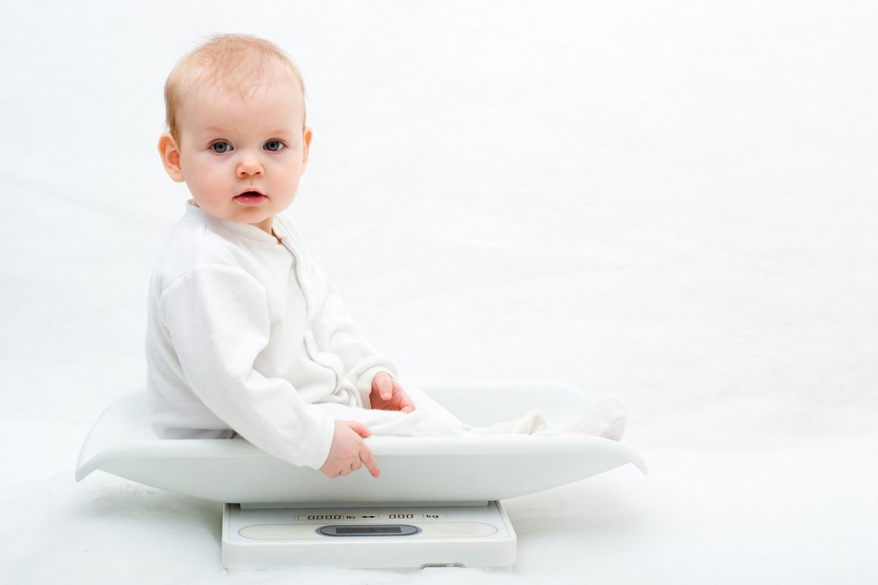 baby on scales on white background, with copy space