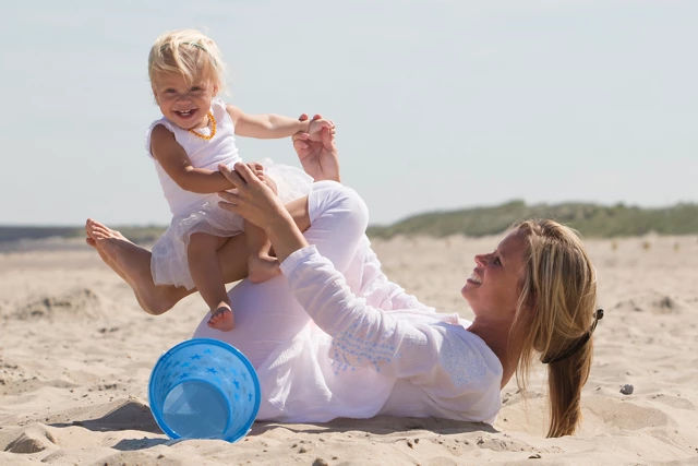 peuter-meisje-mama-spelen-strand-emmer