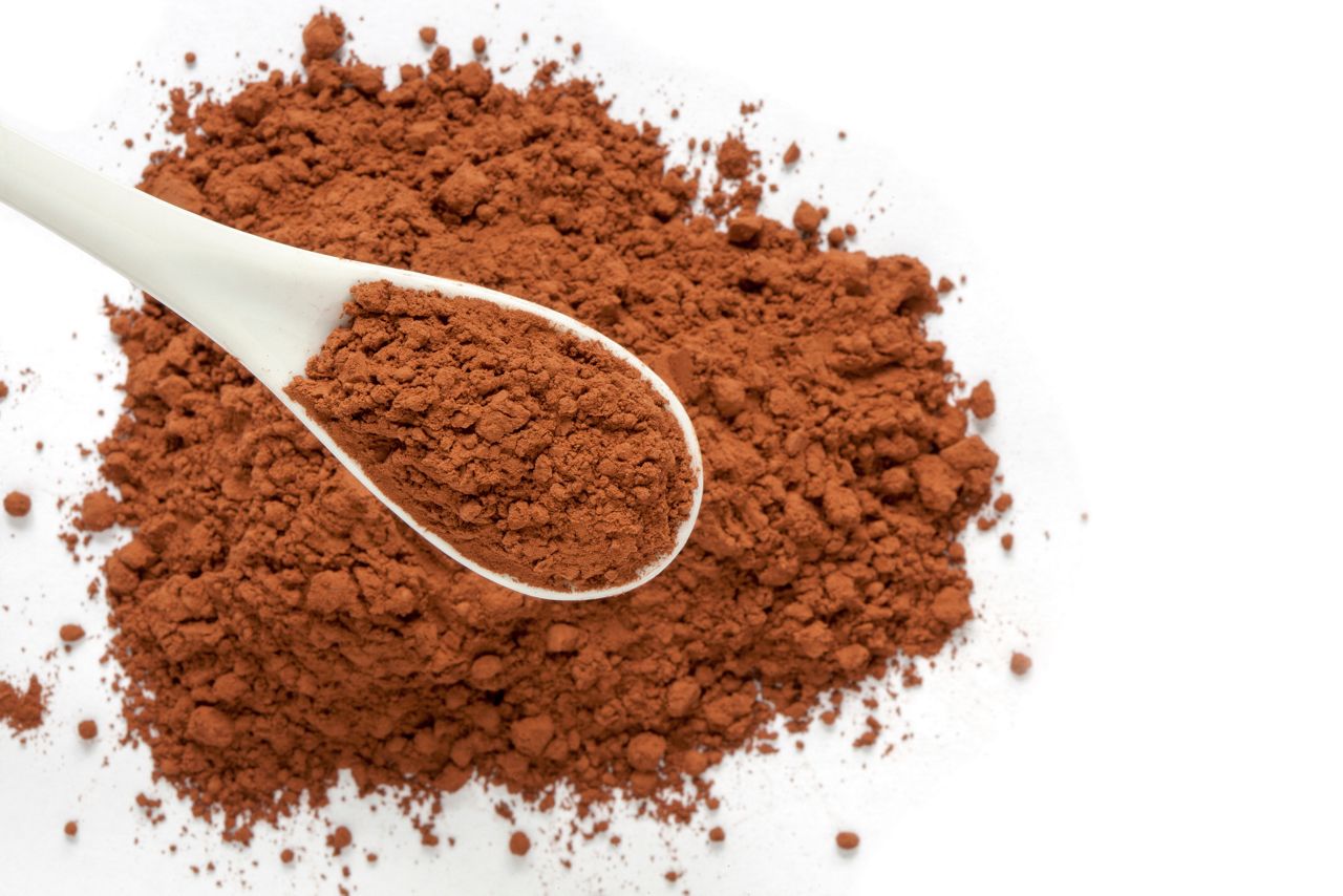 Cocoa powder in spoon on cacao powder background with empty place for your text.