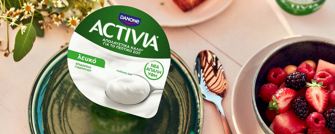 Γυναίκα που τρώει γιαούρτι Activia στην παραλία