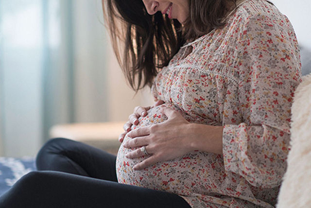 pregnancy mum hands on bump sofa