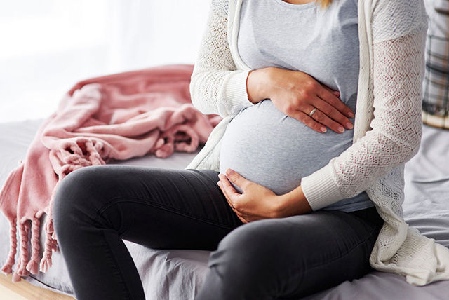 mujer sosteniendo su panza de 38 semanas de embarazo con top azul